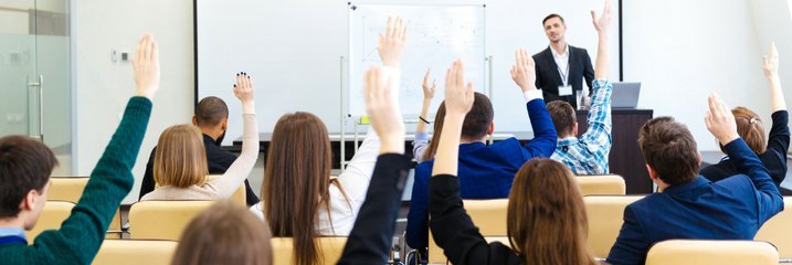 Classroom full of students with their hands up